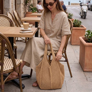 Bolsa de crochê artesanal marrom sendo usada no dia a dia em ambiente urbano elegante com look casual sofisticado
