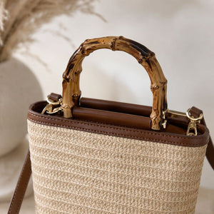 Bolsa de praia de palha com couro marrom e alça de bambu vista em ângulo