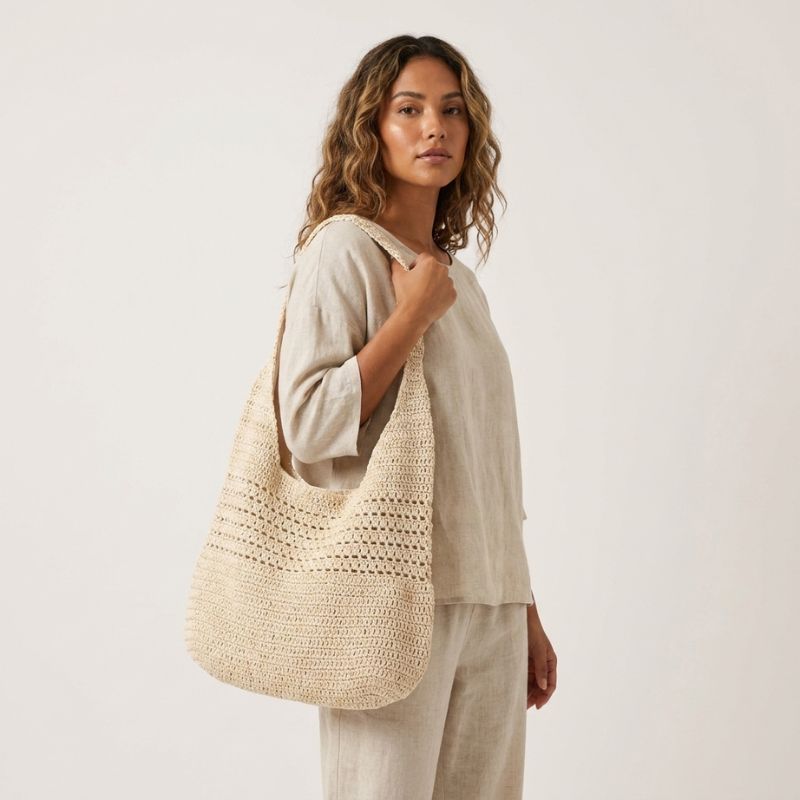 Bolsa de praia de crochê bege usada no ombro em look de verão