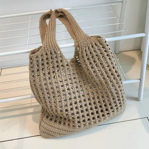Bolsa de praia em crochê bege com trama vazada apoiada sobre móvel claro