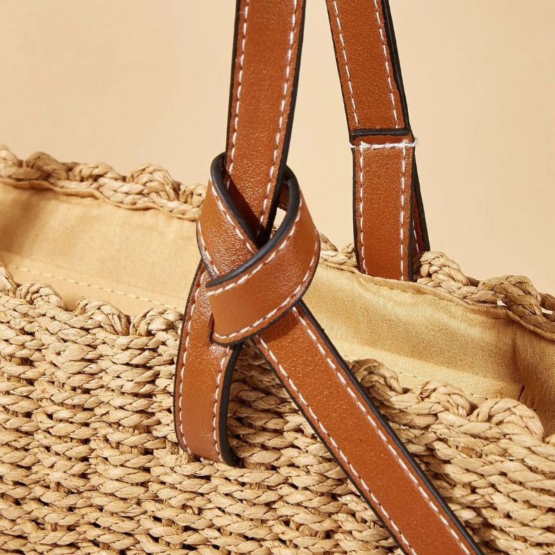 Detalhe das alças marrons da bolsa de praia de palha natural