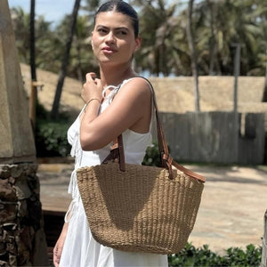 Mulher carregando bolsa de praia de palha em ambiente tropical