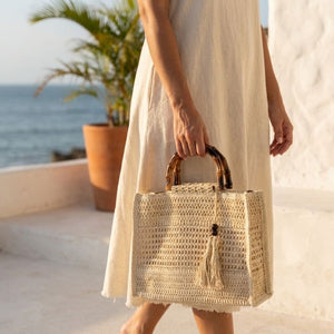 Mulher carregando Bolsa de Palha Aveline Bege em ambiente de verão