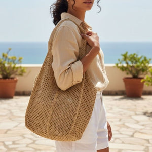 Mulher usando Bolsa Venezia Cáqui no ombro em ambiente à beira-mar