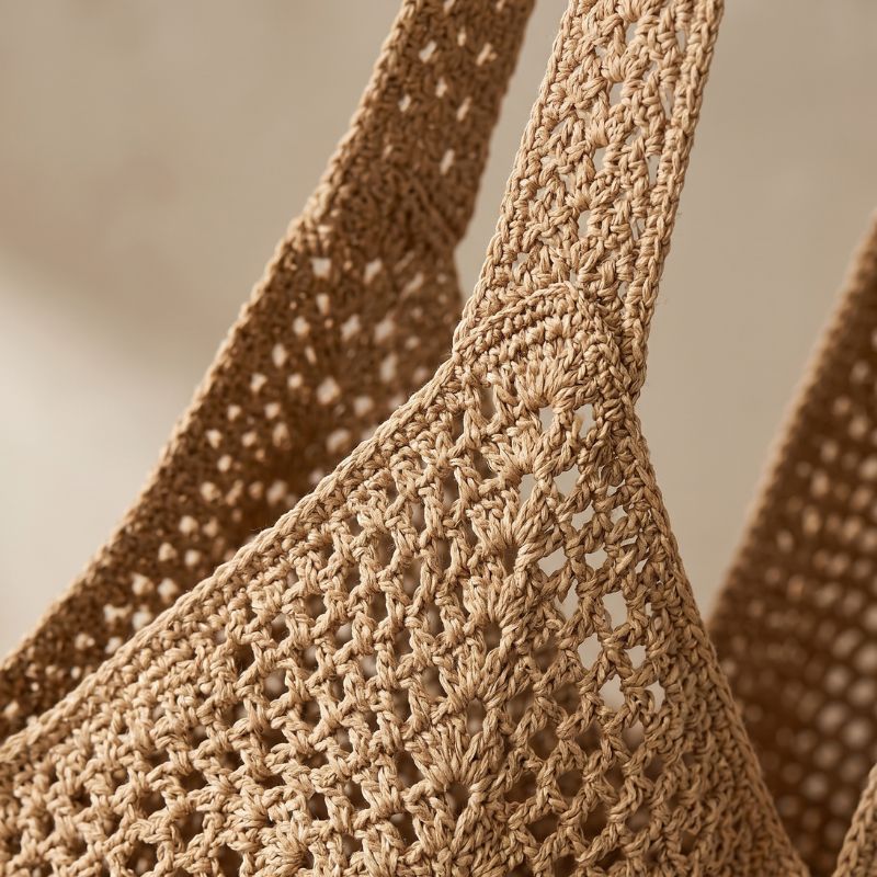 Detalhe da textura em crochê da bolsa de praia marrom mostrando acabamento artesanal e qualidade
