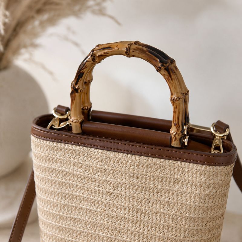Bolsa de praia de palha com couro marrom e alça de bambu vista em ângulo