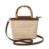 Bolsa de praia de palha com alça de bambu e couro marrom em fundo claro